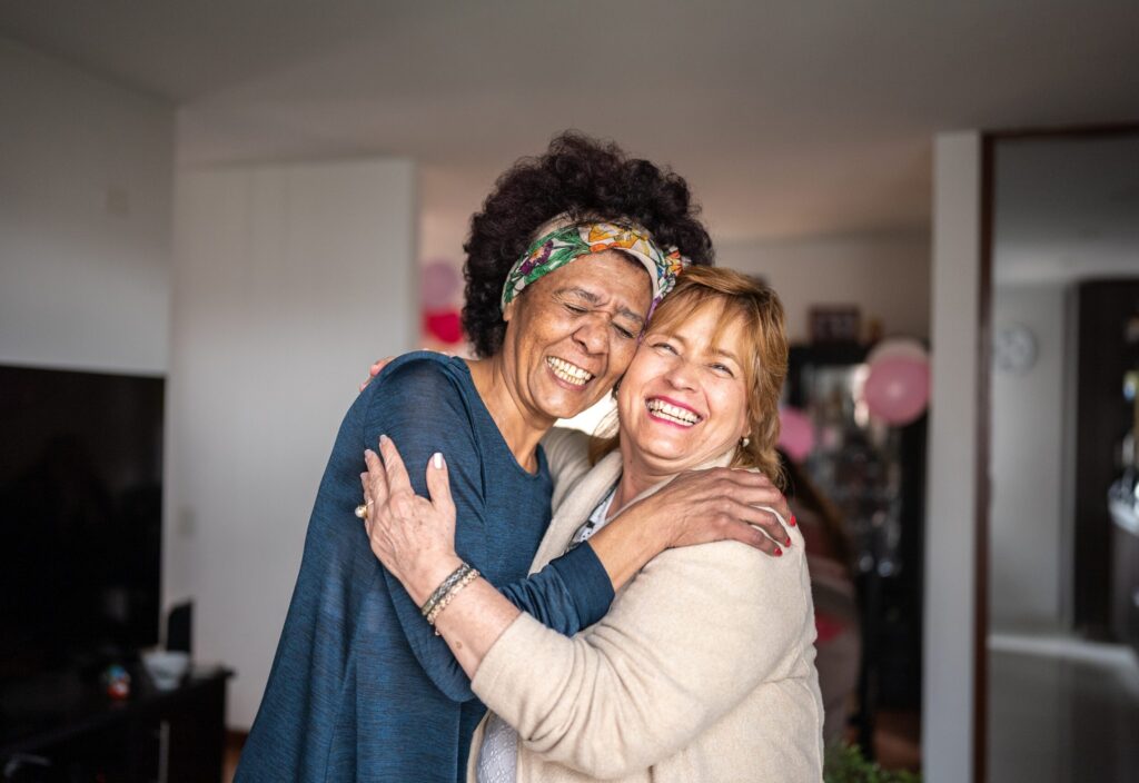 Portrait of senior friends embracing at home